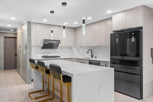 kitchen with light stone counters, a breakfast bar area, stainless steel appliances, light wood-style flooring, and a kitchen island