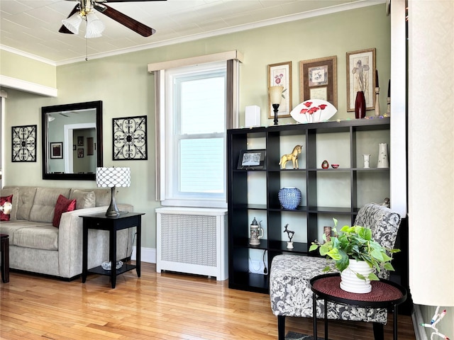 living area with crown molding, wood-type flooring, a ceiling fan, and radiator