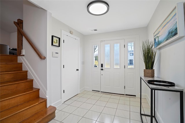 foyer entrance featuring stairway, light tile patterned flooring, baseboards, and visible vents