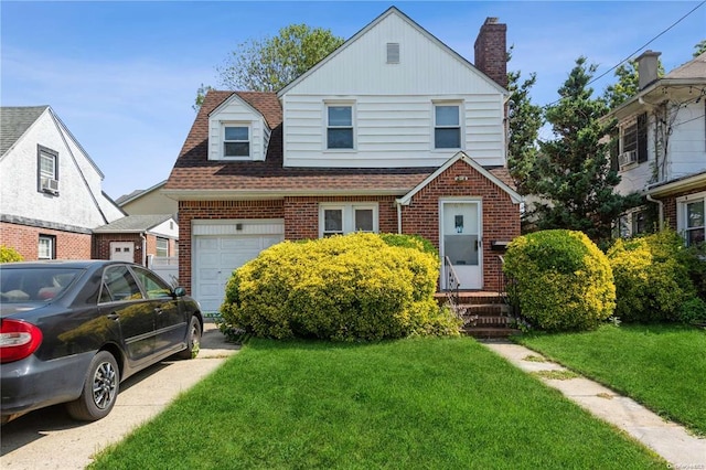 view of front of house with brick siding, a front lawn, concrete driveway, roof with shingles, and a chimney