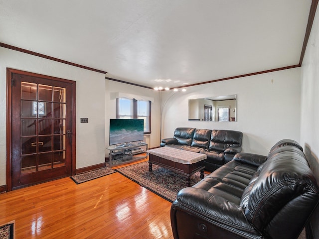 living area featuring baseboards, crown molding, and light wood finished floors