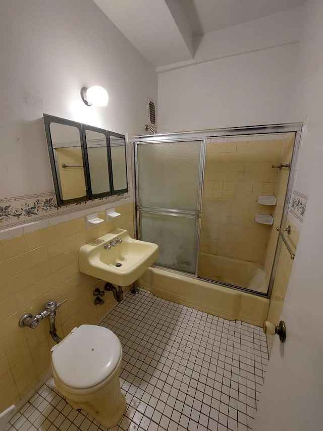 bathroom with enclosed tub / shower combo, tile patterned flooring, a sink, tile walls, and wainscoting