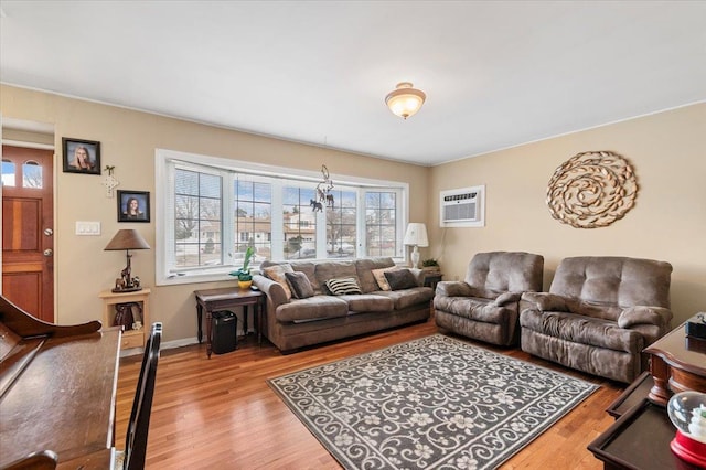 living room with a wall mounted air conditioner, wood finished floors, and baseboards