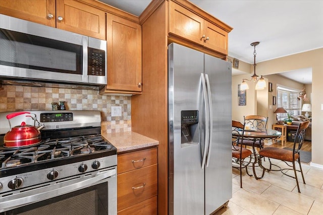 kitchen with stainless steel appliances, tasteful backsplash, light tile patterned flooring, and brown cabinets