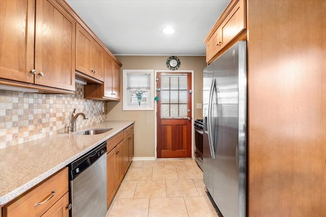 kitchen featuring light tile patterned floors, stainless steel appliances, a sink, backsplash, and light stone countertops