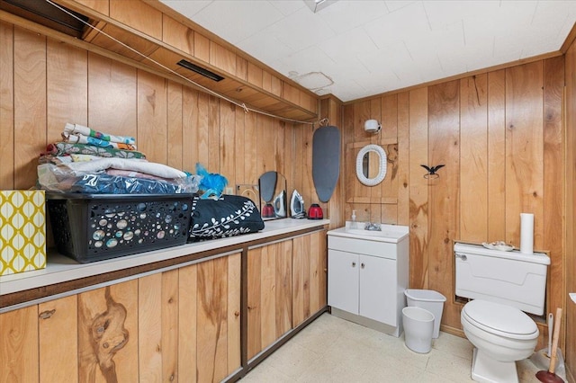 bathroom with wood walls, a sink, toilet, and tile patterned floors