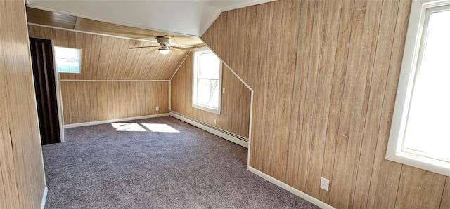 additional living space with wood walls, carpet, a baseboard heating unit, and vaulted ceiling