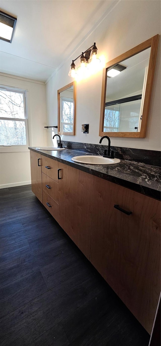 full bathroom with double vanity, visible vents, a sink, and wood finished floors