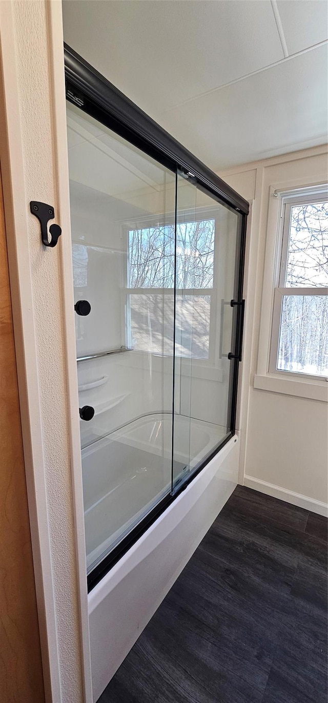 full bath featuring enclosed tub / shower combo, wood finished floors, and baseboards