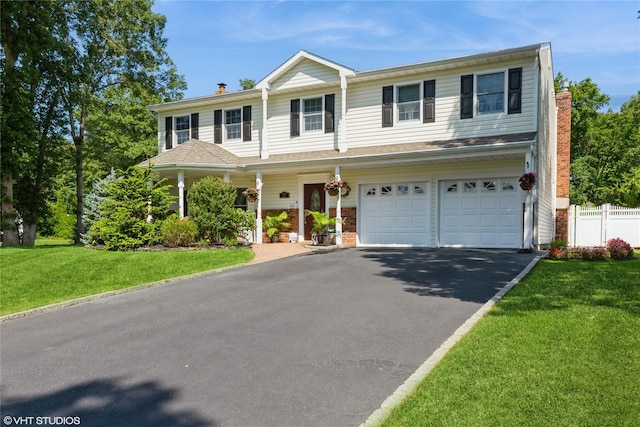 view of front of home with a chimney, aphalt driveway, an attached garage, fence, and a front lawn