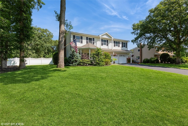 view of front of property featuring aphalt driveway, a front yard, fence, and a garage