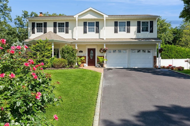 view of front of home with driveway, a front lawn, an attached garage, and fence