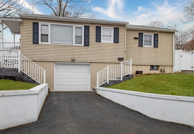 view of front of property with driveway, an attached garage, fence, and a front yard