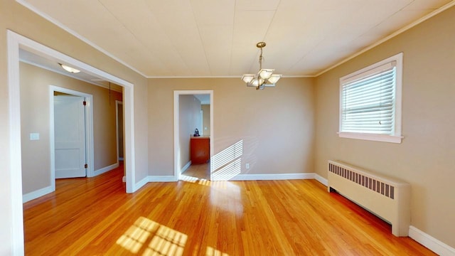 spare room with light wood-style floors, ornamental molding, and radiator heating unit