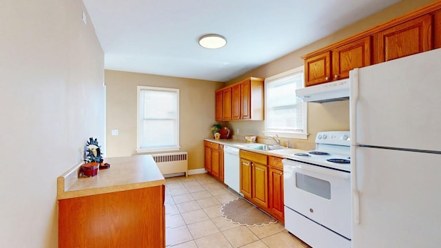 kitchen with under cabinet range hood, white appliances, a sink, light countertops, and radiator