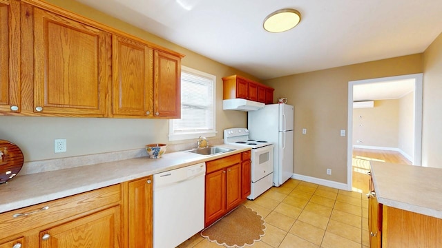 kitchen featuring light tile patterned floors, white appliances, a sink, baseboards, and light countertops