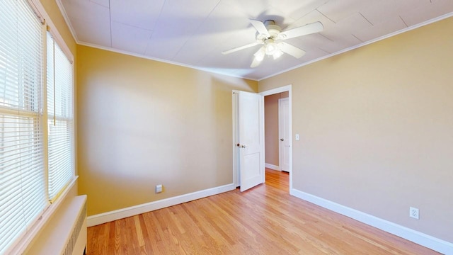 empty room with light wood finished floors, a ceiling fan, baseboards, and crown molding