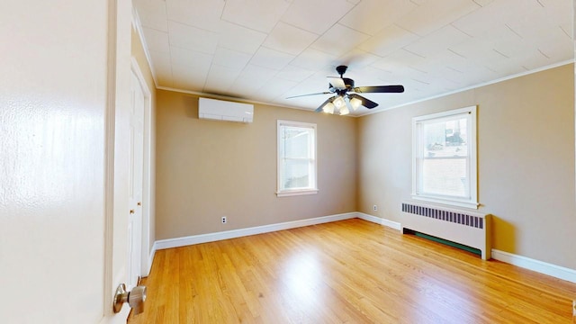 spare room with a wall unit AC, light wood-style flooring, baseboards, ornamental molding, and radiator