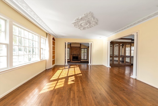 unfurnished living room with baseboards, a fireplace, hardwood / wood-style flooring, and crown molding