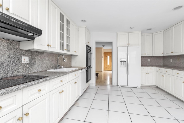 kitchen with light tile patterned floors, under cabinet range hood, a sink, white cabinets, and black appliances