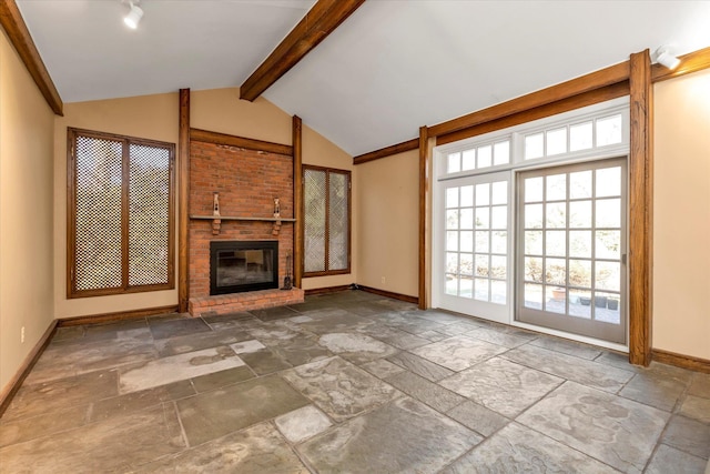 unfurnished living room featuring a fireplace, baseboards, vaulted ceiling with beams, and stone tile floors