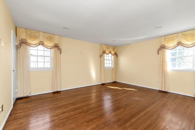 spare room with hardwood / wood-style floors and baseboards