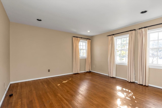 spare room featuring baseboards, wood finished floors, and recessed lighting