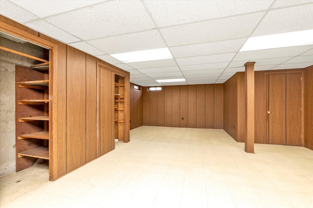 finished below grade area with tile patterned floors, a paneled ceiling, and wooden walls