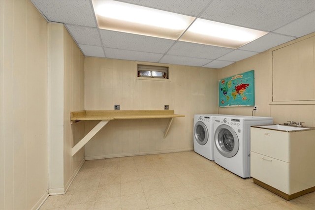 clothes washing area featuring a sink, washer and clothes dryer, and light floors