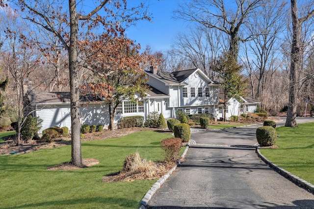 view of front of house with aphalt driveway and a front lawn