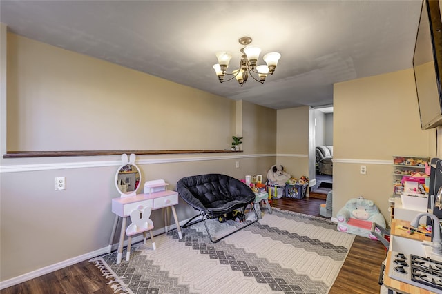 rec room featuring a chandelier, wood finished floors, and baseboards