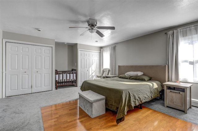 bedroom with multiple closets, light carpet, and ceiling fan