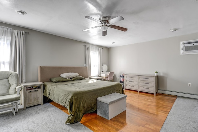 bedroom with ceiling fan, an AC wall unit, a baseboard radiator, and light wood-style floors