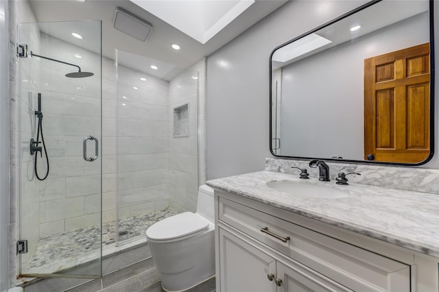 bathroom featuring a stall shower, vanity, toilet, and a skylight