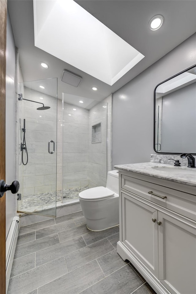 full bathroom with wood finish floors, toilet, a baseboard heating unit, vanity, and a shower stall