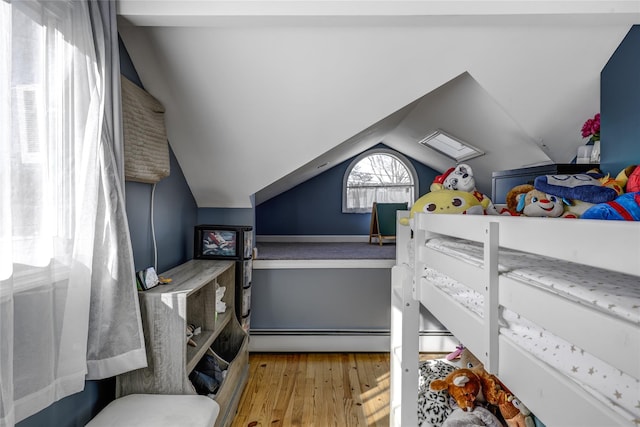 bedroom featuring vaulted ceiling, baseboard heating, and wood finished floors