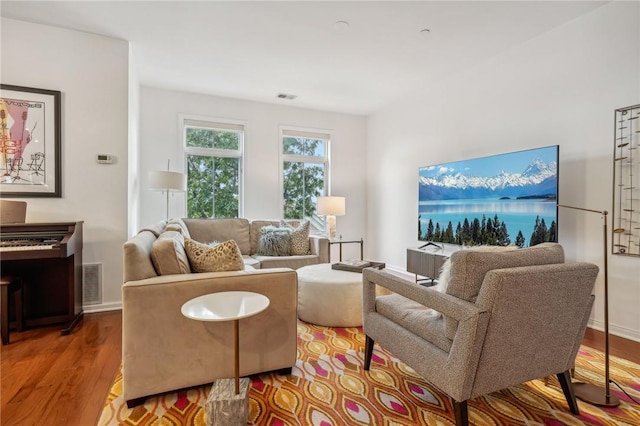 living room with visible vents, baseboards, and wood finished floors