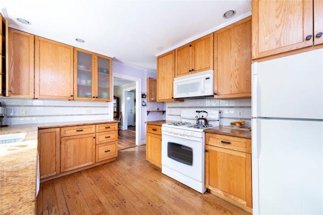 kitchen featuring white appliances, tasteful backsplash, light wood-style flooring, glass insert cabinets, and light stone counters