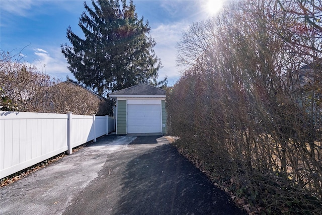 detached garage featuring driveway and fence