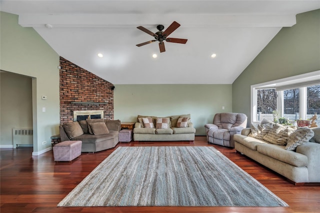 living area featuring radiator, a brick fireplace, dark wood finished floors, and beamed ceiling