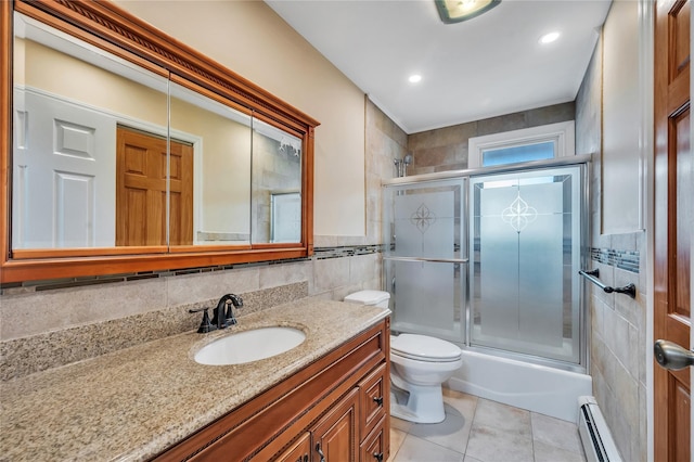 bathroom featuring tile patterned flooring, toilet, vanity, tile walls, and baseboard heating