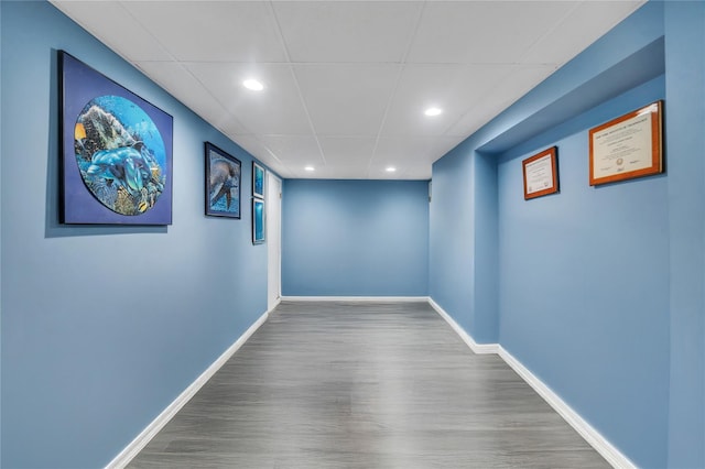 interior space featuring recessed lighting, a drop ceiling, baseboards, and wood finished floors