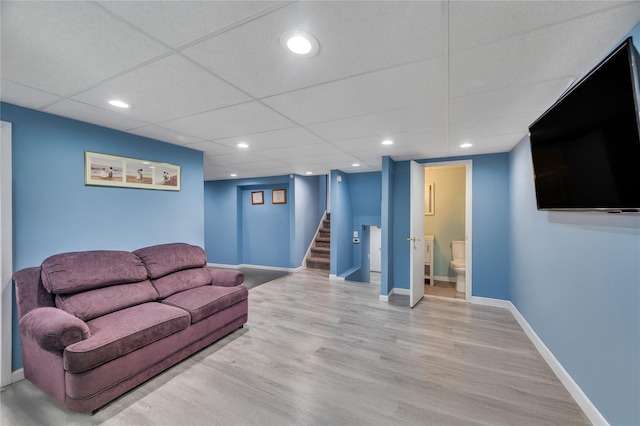 living area with baseboards, a drop ceiling, light wood-style flooring, stairway, and recessed lighting