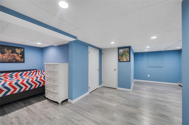 bedroom with recessed lighting, light wood-style flooring, a baseboard heating unit, a drop ceiling, and baseboards