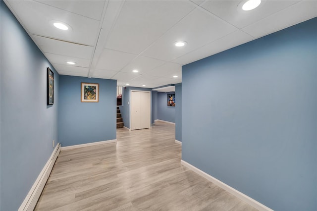 spare room featuring a baseboard radiator, recessed lighting, baseboards, light wood-style floors, and stairway