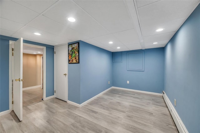 finished basement with a baseboard heating unit, recessed lighting, light wood-style floors, and baseboards