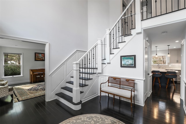 stairway featuring hardwood / wood-style flooring, a high ceiling, and a decorative wall