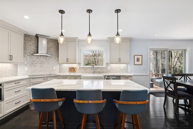 kitchen featuring dark wood-type flooring, a sink, wall chimney range hood, appliances with stainless steel finishes, and tasteful backsplash