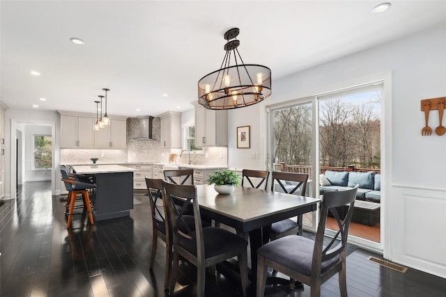 dining space with recessed lighting, a wainscoted wall, a notable chandelier, visible vents, and dark wood finished floors