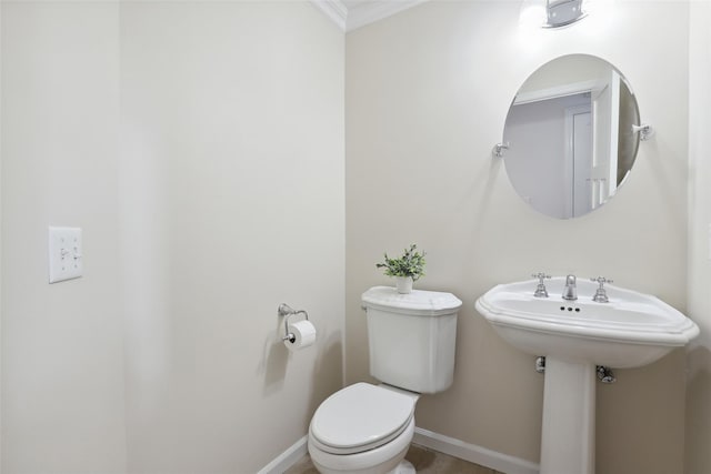 bathroom with ornamental molding, toilet, and baseboards